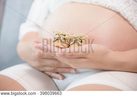 Pregnant Woman Holding Small Baby Shoes Relaxing At Home