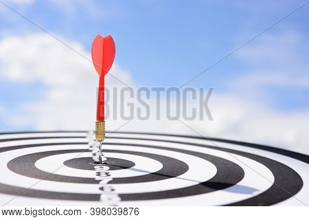 Red Dart Arrow Hitting In The Target Center Of Dartboard With Blue Sky Background