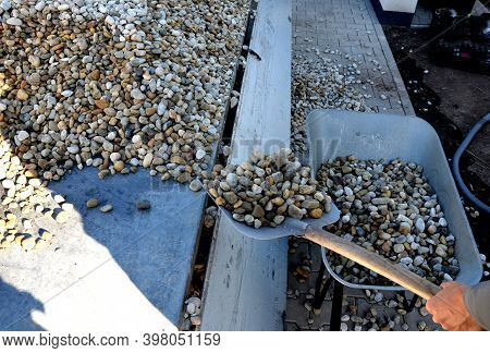 Delivery Of Gray River Pebbles Like Mulch To Flower Beds In The Garden Using A Wheelbarow From The B