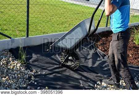 Delivery Of Gray River Pebbles Like Mulch To Flower Beds In The Garden Using A Wheelbarow From The B