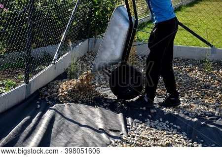 Delivery Of Gray River Pebbles Like Mulch To Flower Beds In The Garden Using A Wheelbarow From The B