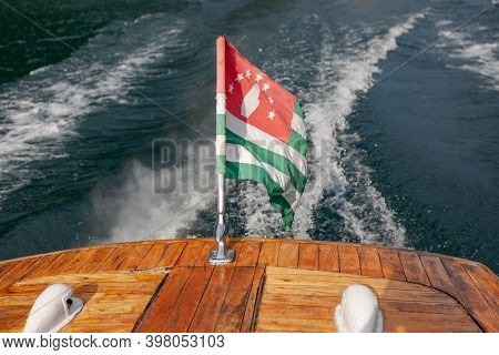 Pleasure Boat With Abkhazian Flag Floats On Lake Rizza, View From Behind