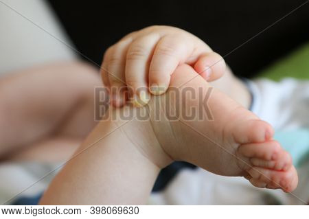 A Detail Picture Of Child´s Hands And Feet. The Child Is Holding Its Feet And Exploring Its Body And