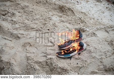 Burning Sports Sneakers Or Gym Shoes On Fire Stand On Sandy Beach Coast. Athlete Burned Out. Physica