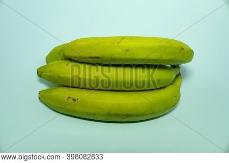 A Bunch Of Unripe Bananas On A Blue Background.