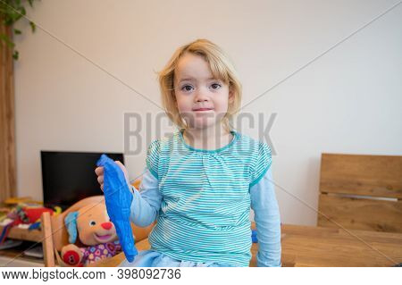 Cute Blonde Girl Playing With Medical Rubber Gloves At Home.