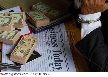 Dollar Banknotes Placed On The Newspaper And A Document Bag On A Wooden Table And A Businessmen Was 