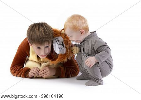 On A White Background, The Kid Plays With His Brother, Dressed In A Carnival Lion Costume. Elder And