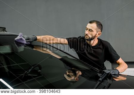 Car Wash And Cleaning At Professional Auto Service Station. Shot Of Handsome Bearded Young Male Work