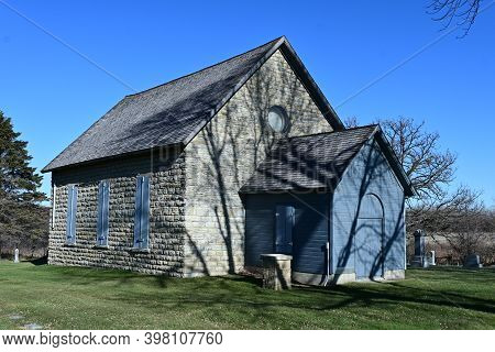 Kenyon, Mn, Usa, November 27, 2020. The Exterior Of The Historic Old Stone Church With Tree Shadows 