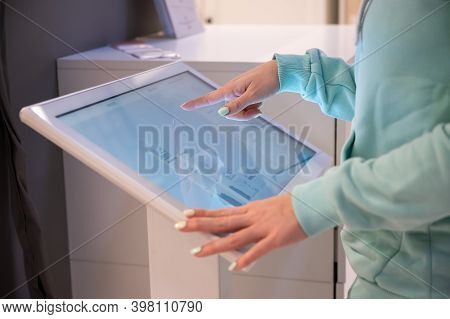 Faceless Woman Touching The Screen Of A Self-service Device In A Store. Device Store Navigator. Self