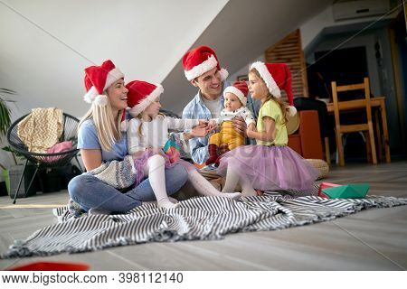 Merry parents spening Christmas time together with their kids at home
