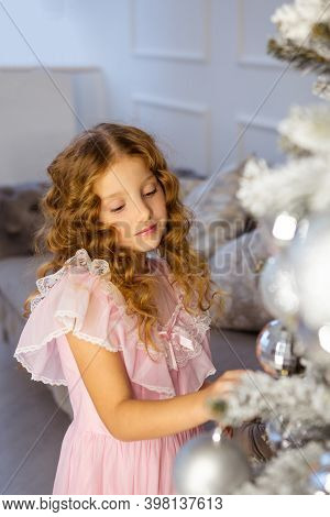 Little Girl Decorate The Christmass Tree, New Year Concept. Kid Near Christmass Tree, Girl In Pink D