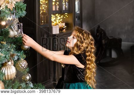 Little Girl In A Festive Dress Decorate The Christmass Tree, New Year Concept. Kid Near Christmass T