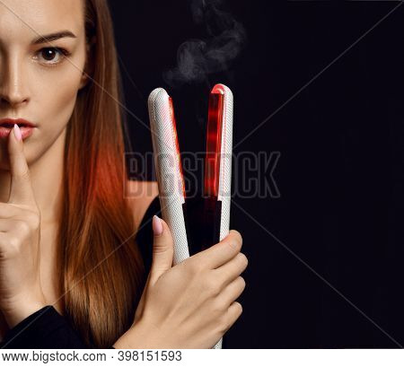 Young Pretty Woman Model Standing And Holding Hair Straightener In Hands While Showing Silence Sign 