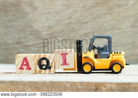 Toy Forklift Hold Letter Block I To Complete Word Aqi (air Quality Index)on Wood Background
