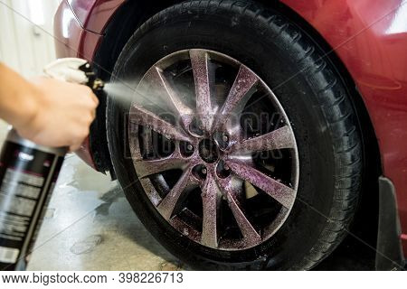 Service Worker Washing Car Wheell At A Car Wash.