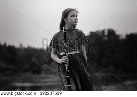 Young Attractive Girl Playing Clarinet In Fall Park