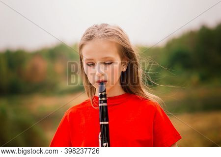 Young Attractive Girl Playing Clarinet, Ebony In Fall Park