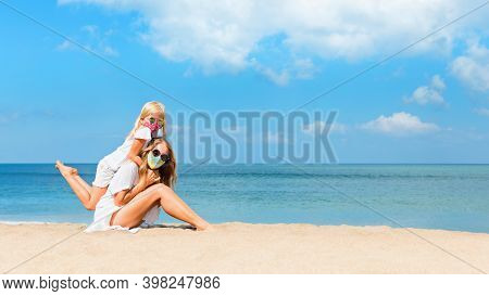 Mother, Child In Masks Have Fun On Sea Beach. New Rules To Wear Cloth Face Covering At Public Places