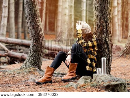 Woman In Yellow Shirt And Hat Siting Under The Tree In The Autumn Forest