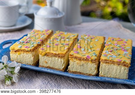 Four Tompouce Cakes With Whipped Cream And Yellow Icing Served In Sunny Spring Garden
