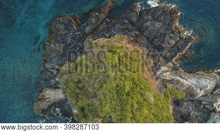 Top down closeup at green island at sea bay aerial. Nobody nature landscape of El Nido Islet, Philippines, Asia, Visayas Archipelago. Tropical exotic trees at rock isle top. Greenery plants on cliff