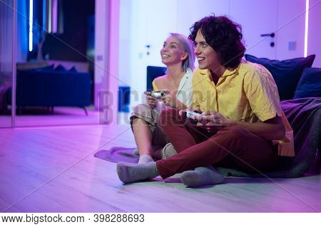 Couple Of Young Adults Playing Video Games At Home. Emotional Diverse Gamers Holding Joysticks And C