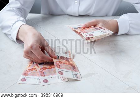 A Girl In A White Shirt At The Table Counts Money, A Bank Employee