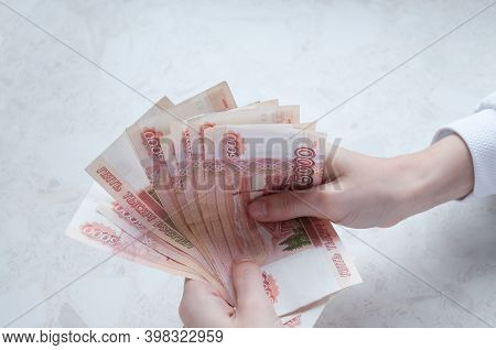 Women's Hands Hold A Bundle Of Large Bills Of Five Thousand Rubles Over The Table