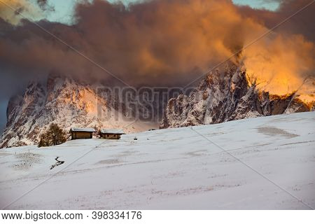 Small cottage in magic sunset in Dolomite mountains, Alpe di Siusi, Italy in winter