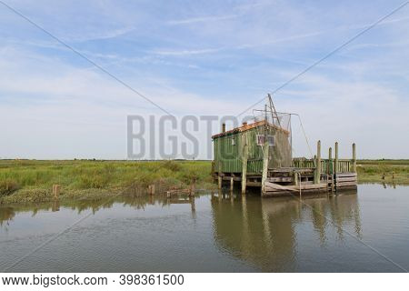 Green cabin at wooden boat dock in landscape at French Charente