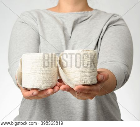 Woman Holds In Hand A White Elastic Bandage For The Body, Gray Background