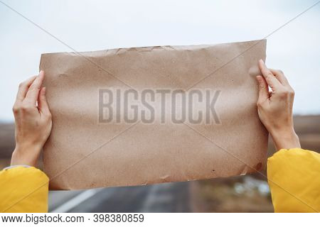 Closeup View Of A Womans Hands Wearing Yellow Jacket Holding A Poster Blank Paper On The Side Of An 
