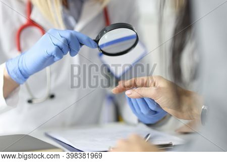 Dermatologist Doctor Looking At Patients Skin On Hands Using Magnifying Glass In Clinic Closeup. Dia