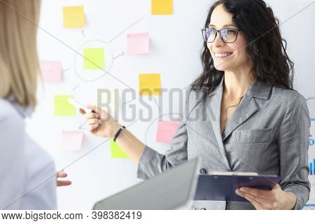 Business Woman Showing Colleague With Ballpoint Pen Stickers On Chalkboard. Conducting Trainings Con