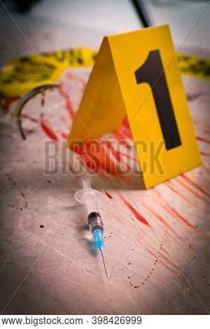 Syringe In Blood And Crime Scene Marker On Marble Table, Closeup