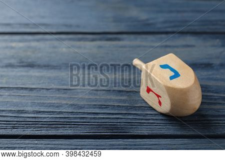 Hanukkah Traditional Dreidel With Letters Nun And Gimel On Blue Wooden Table. Space For Text