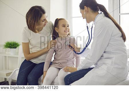 Young Smiling Woman Pediatrician Using Stethoscope For Checking Up Little Smiling Girl