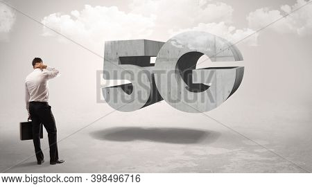 Rear view of a businessman standing in front of 5G abbreviation, modern technology concept