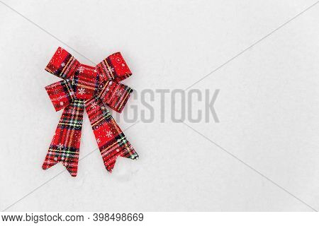 Christmas Decoration-red Textile Bow Lying On The Snow. Space For Text. Red Bow On White Snow Backgr
