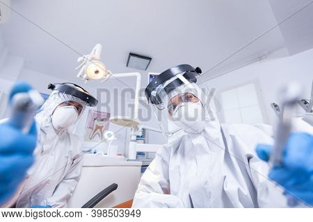 Patient Pov Of Orthodontist And Assistan Doing Procedure For Mouth Hygine In Coverall. Stomatology T
