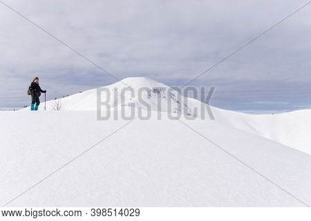 Senior Woman Is Snowshoe Hiking In Alpine Snow Winter Mountains. Allgau, Bavaria, Germany.