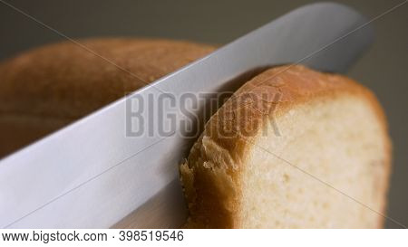 Cutting Bread Isolated On Grey Background. Stock Footage. Close Up Of Hand Cutting A Freshly Baked L