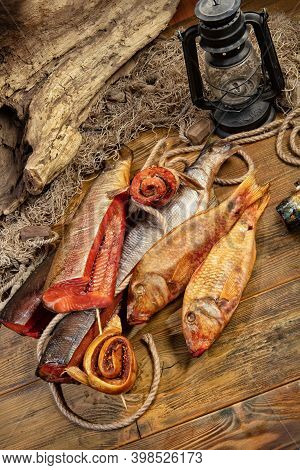 Different Kinds Of Smoked Fish And Fushing Net On A Wooden Desk