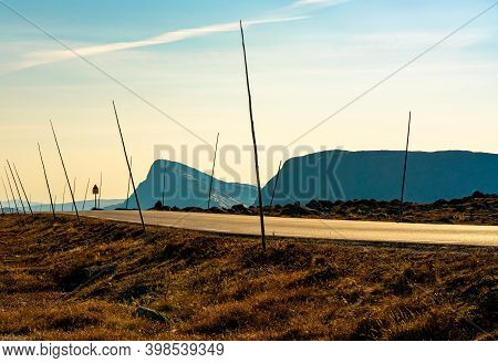 Long Road In The Mountains With Road Side Marking Sticks Ready For Winter, On The Side Is Mount Biti