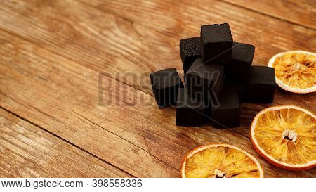 Coals For Hookah On Wooden Background With Dry Oranges. Place For Text