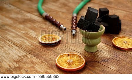 Coals For Hookah On Wooden Background With Dry Oranges And Bowl. Place For Text
