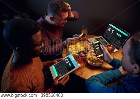 Gadgets. Excited Fans In Bar With Beer And Mobile App For Betting, Score On Their Devices. Screen Wi
