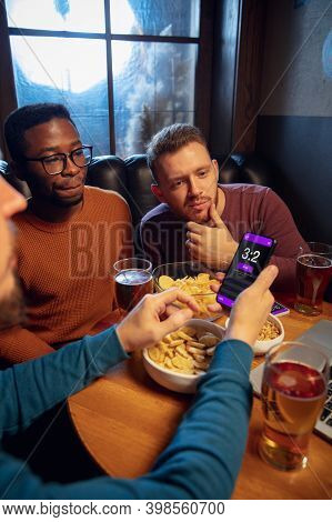 Tensioned. Excited Fans In Bar With Beer And Mobile App For Betting, Score On Their Devices. Screen 